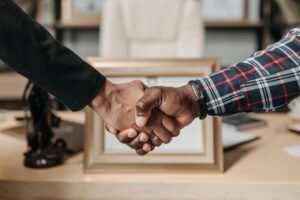 Close-up of a handshake between two professionals in an office environment.